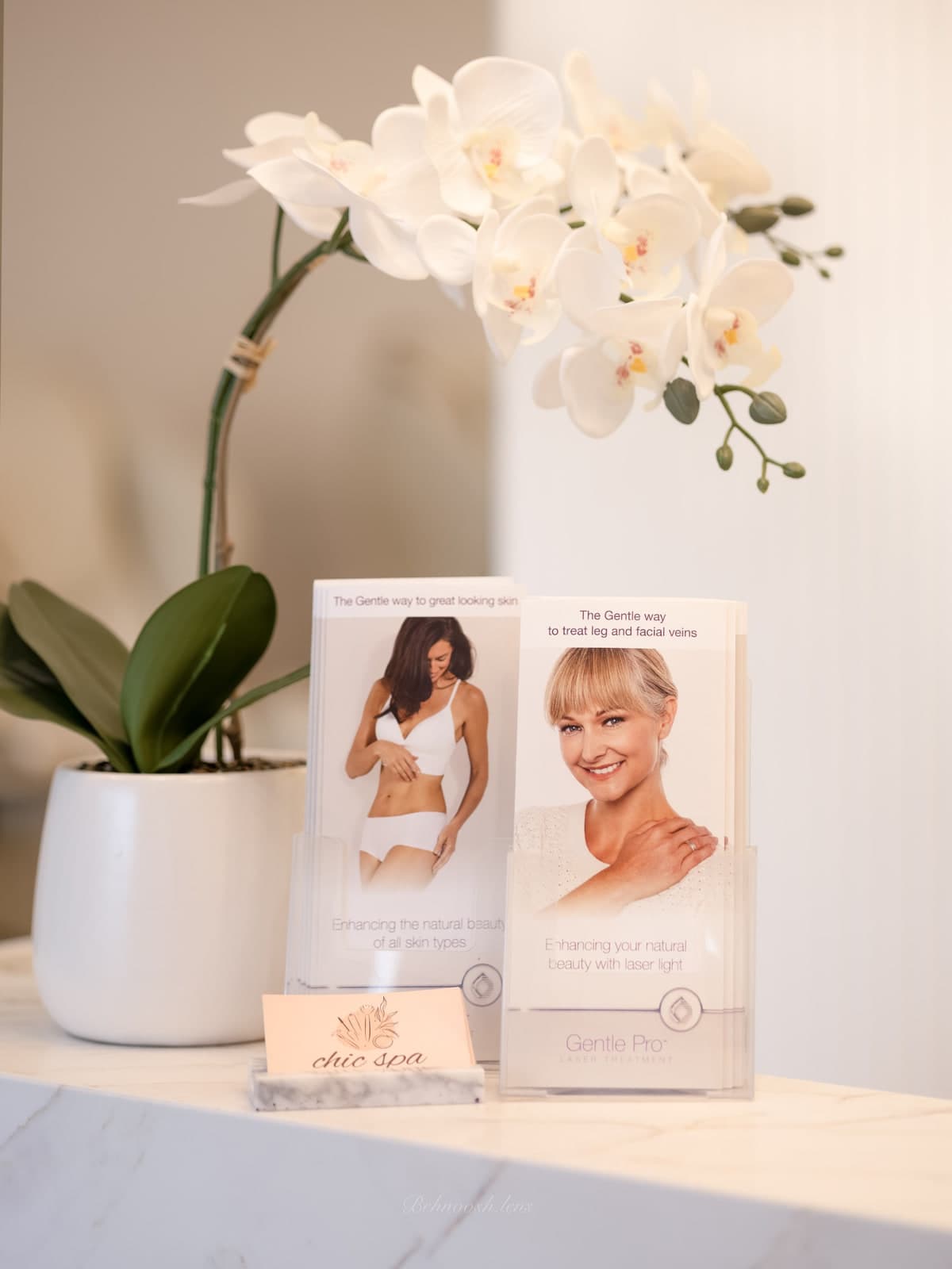 White orchid, laser treatment brochures and chic spa business cards on the marble front desk